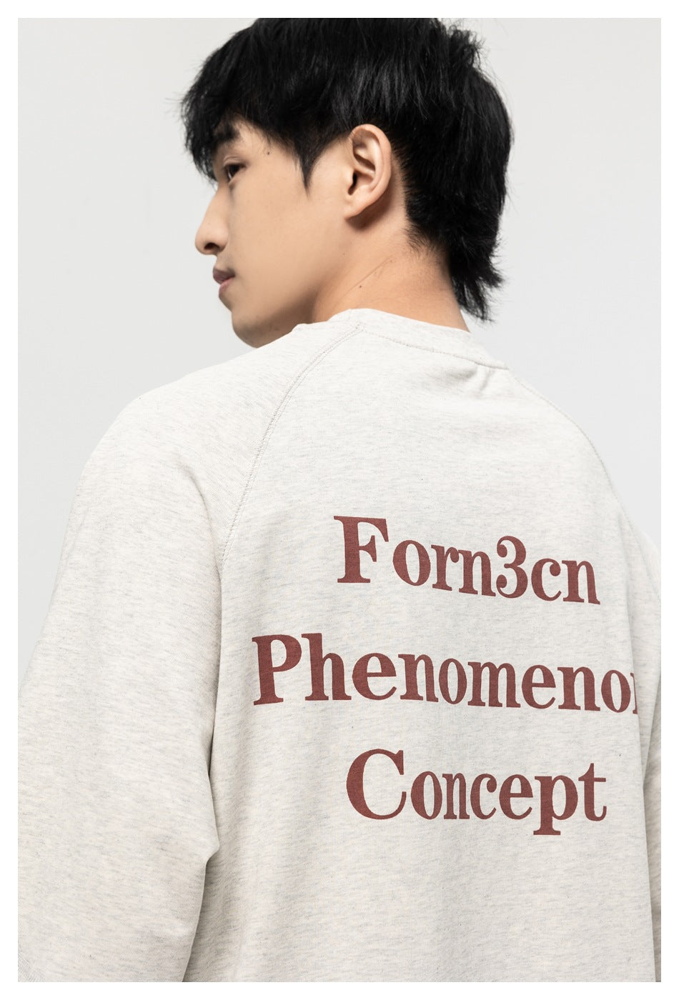 Close rear view of a model wearing an off-white raglan T-shirt with large burgundy English text across the back.