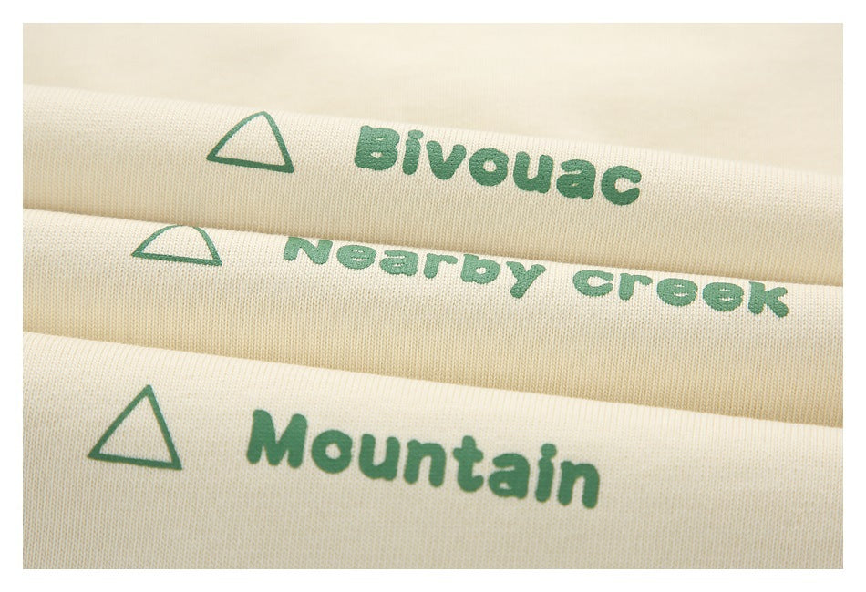 Three folded ivory fabrics show green triangle prints labeled Bivouac, Nearby Creek, and Mountain.