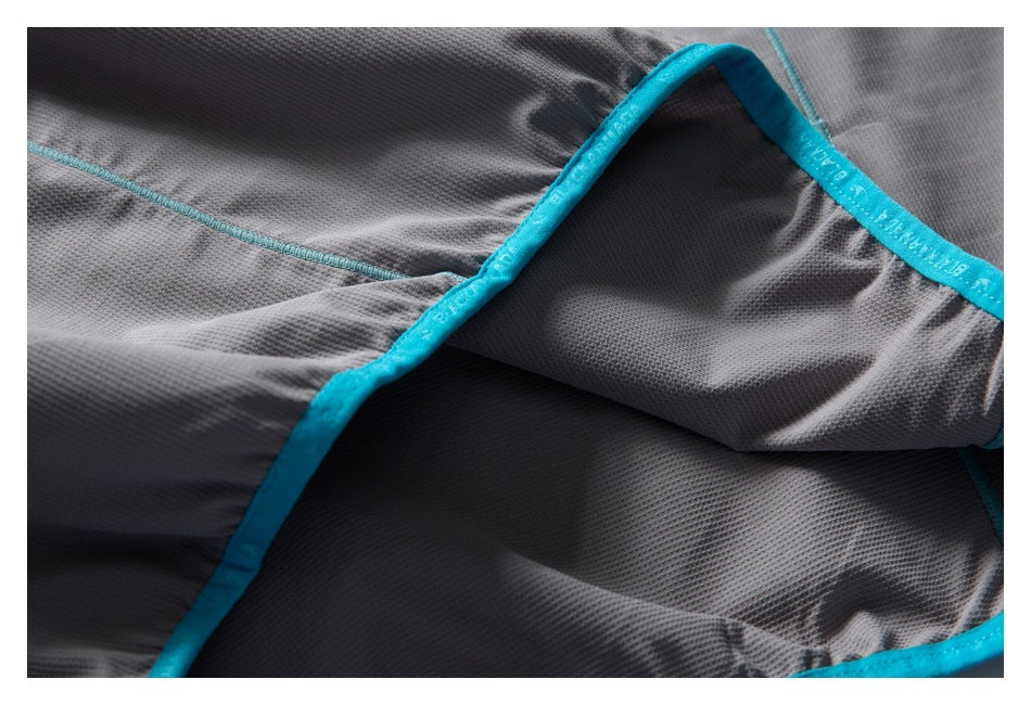 Close-up of gray garment fabric with bright turquoise binding and stitching.
