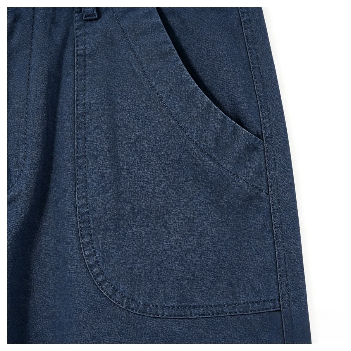 Close-up of a curved front pocket on blue trousers, with visible stitching and a slanted opening.