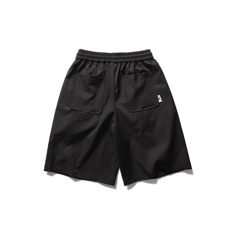 Back view of black knee-length shorts with elastic waistband and two large patch pockets, flat lay