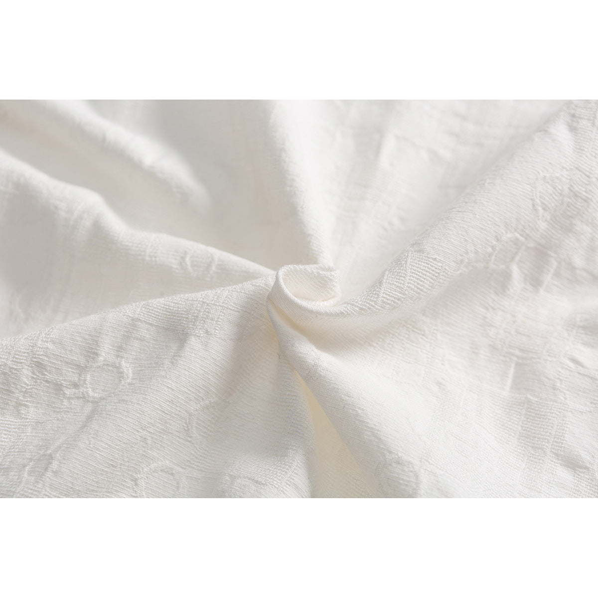 Close-up of white textured fabric gathered to show its raised woven pattern.