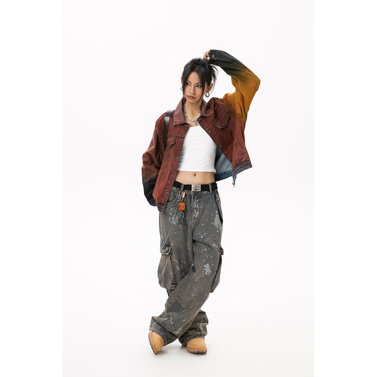 Full-length model wearing an open rust-red color-block denim jacket and loose, splatter-print gray cargo jeans.