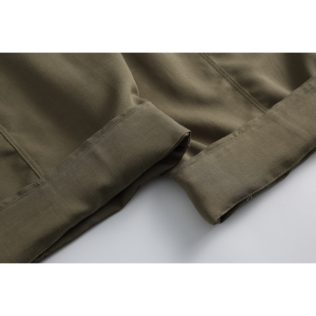 Close-up of olive-brown trouser legs showing folded hems and parallel stitching.