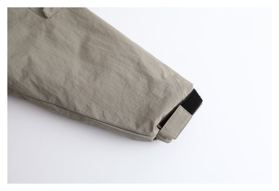 Close-up of the taupe jacket sleeve and cuff with a black hook-and-loop adjustment tab.