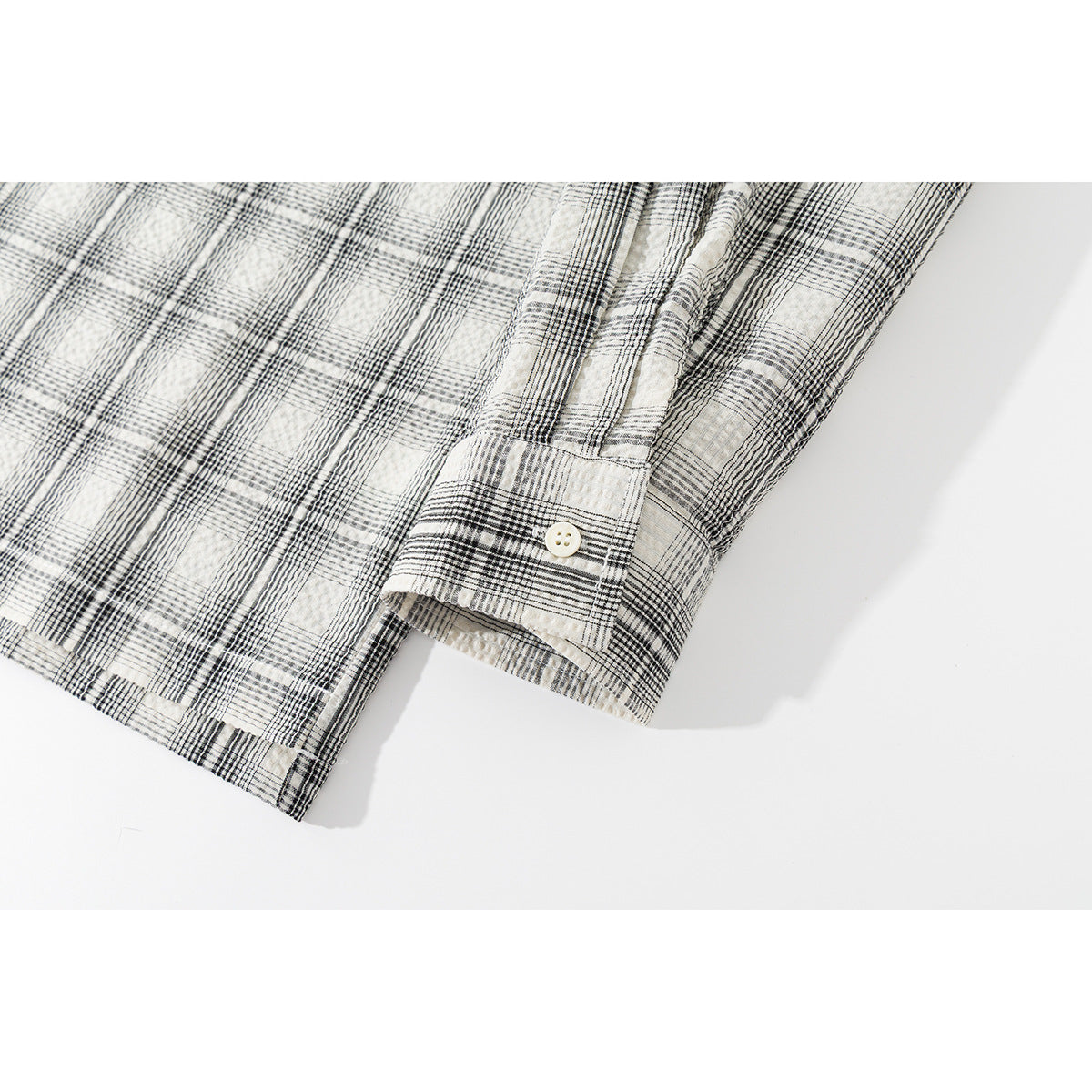 Close-up of the cream and black plaid shirt's buttoned cuff and sleeve.