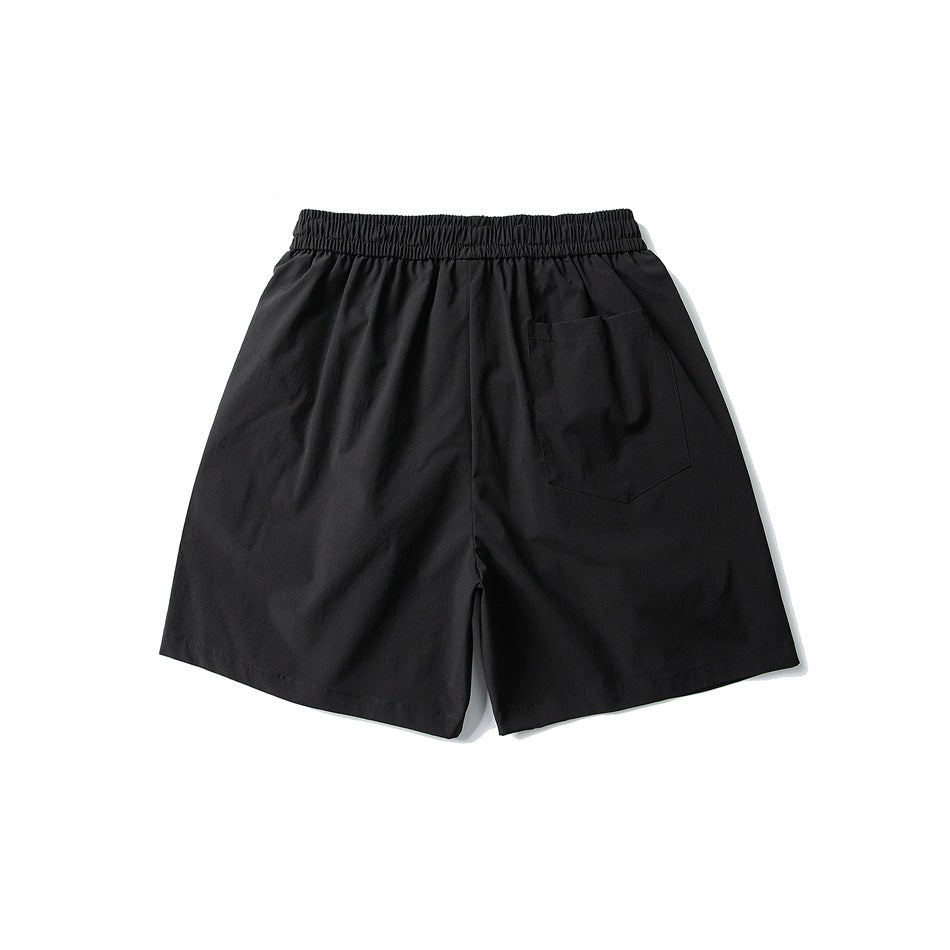 Black shorts laid flat, back view, with an elastic waistband and a single rear pocket.