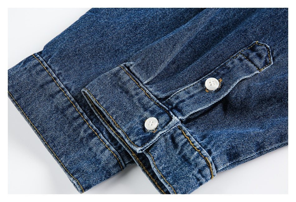 Close-up of a blue denim cuff with gold stitching and two white buttons.