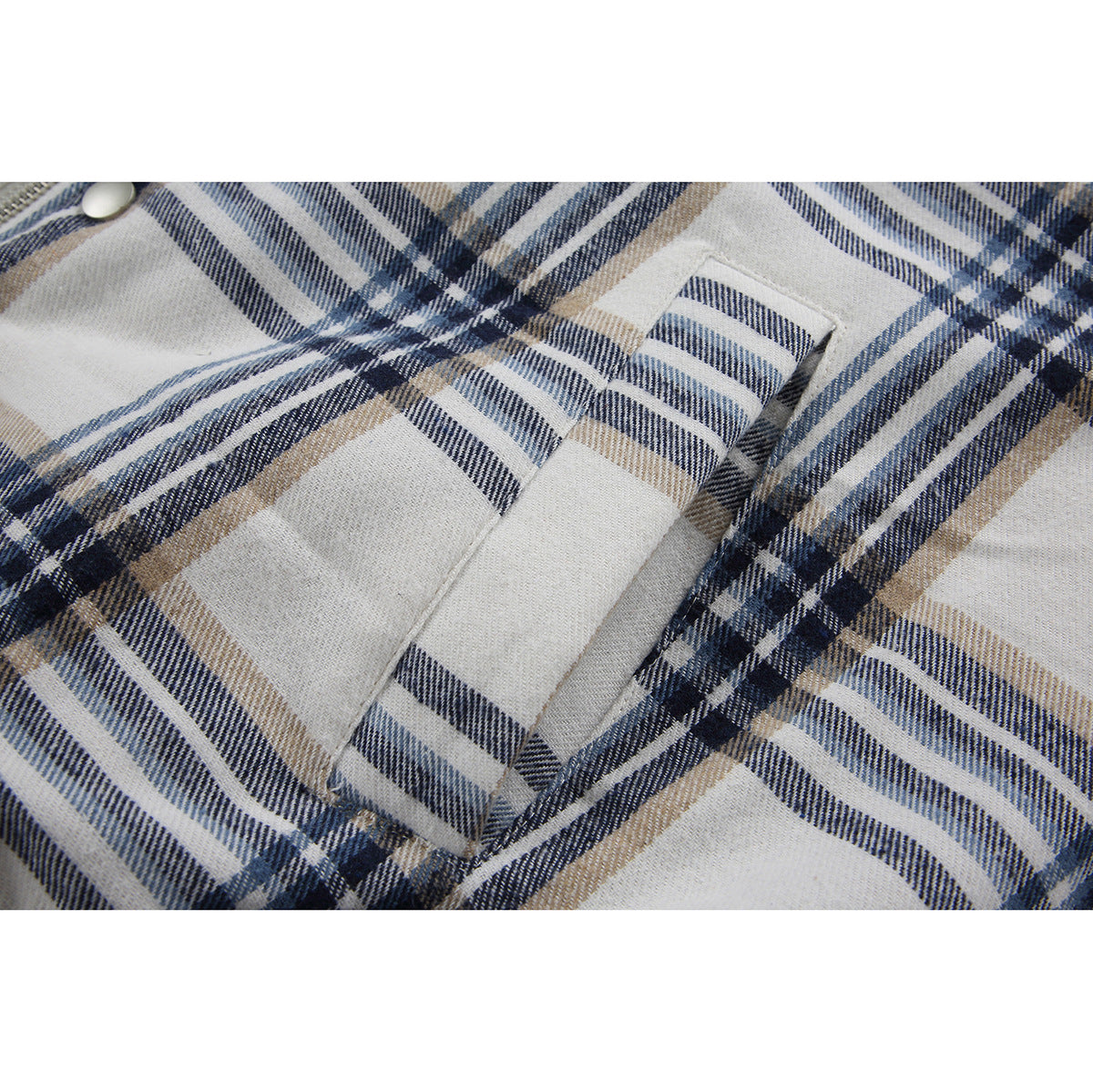 Close-up of a welt pocket on a cream jacket with navy and tan plaid.