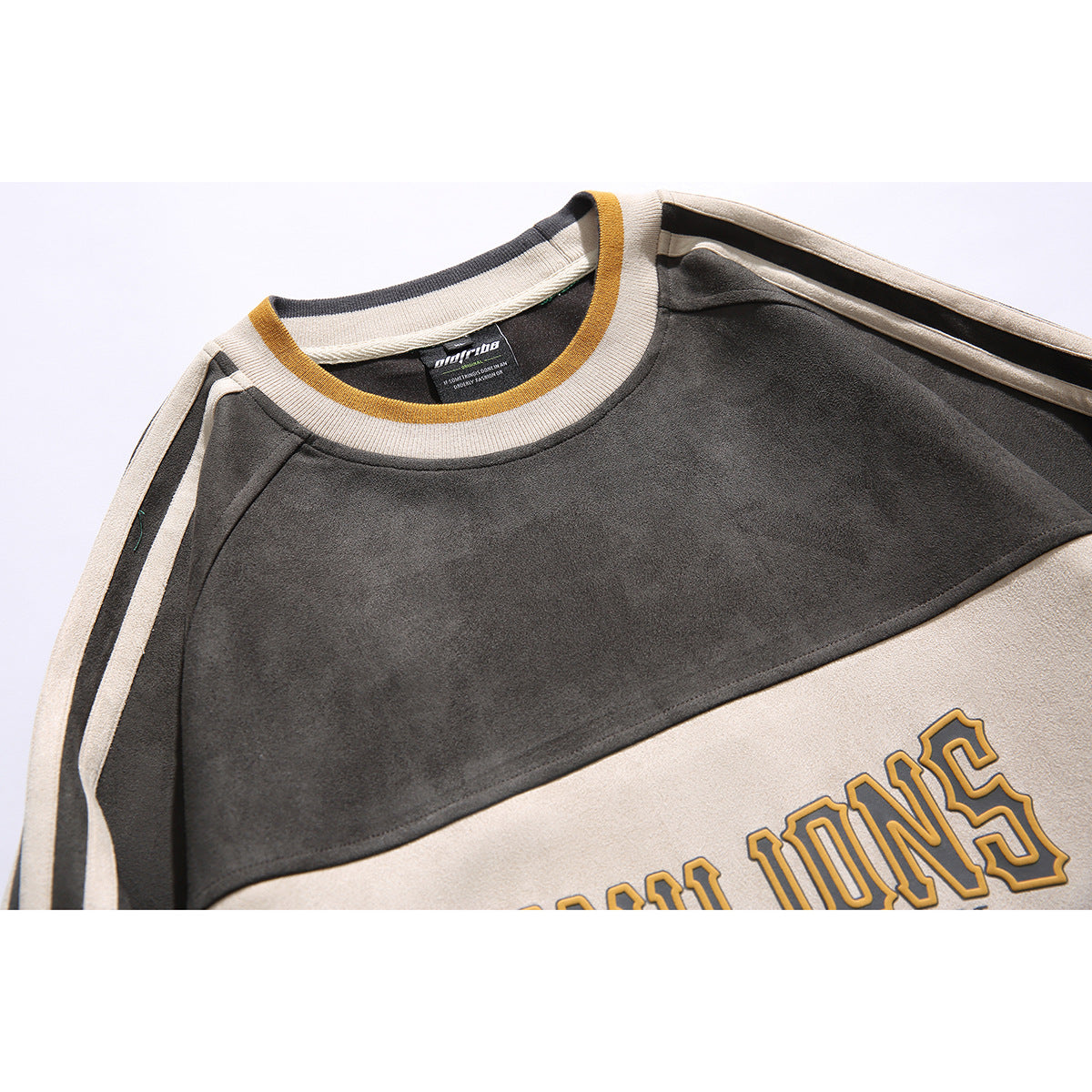 Close-up of a charcoal, cream, and teal color-block sweatshirt showing its striped collar and chest graphic.