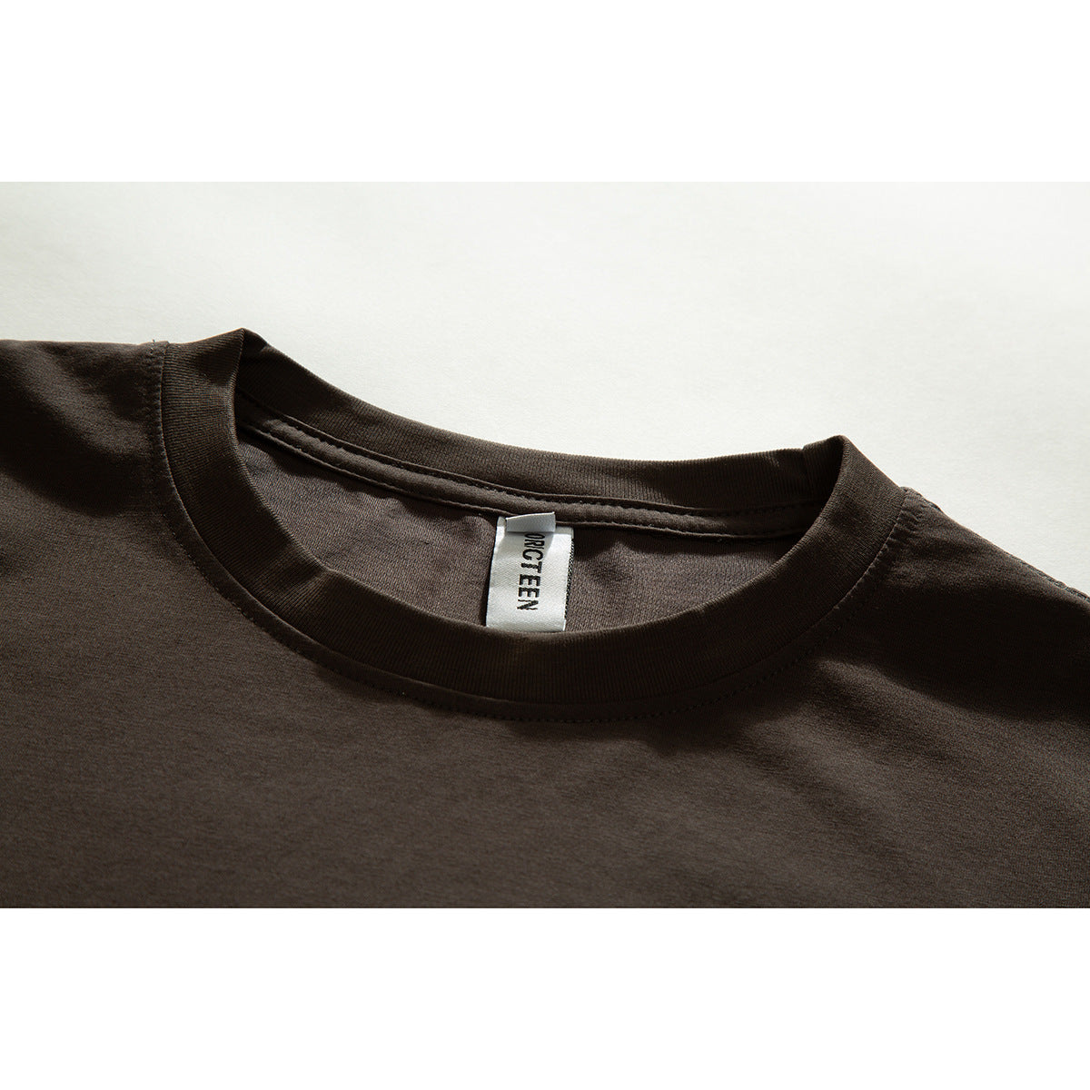 Close-up of a dark brown T-shirt's crew neck and inner brand label.