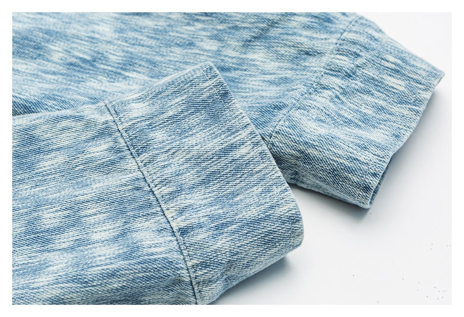 Close-up of light blue washed denim with a folded edge and visible stitching.