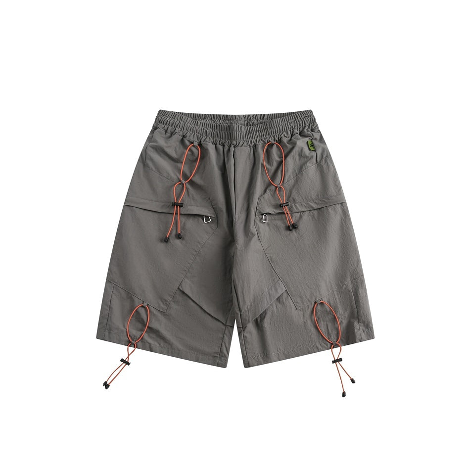 Gray knee-length shorts, front view, with orange toggle cords, angled flap panels and an elastic waistband
