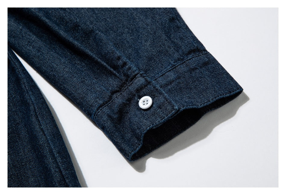 Close-up of a dark indigo garment sleeve cuff with a white button and visible stitching.