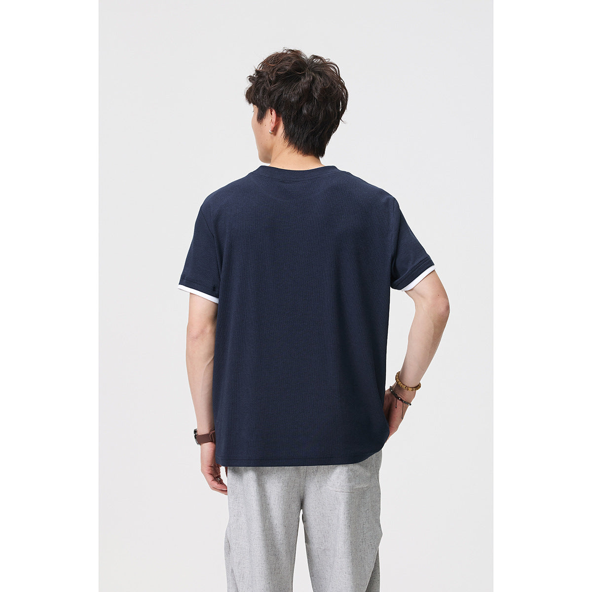 Back view of a model wearing a plain navy T-shirt with white sleeve trim.