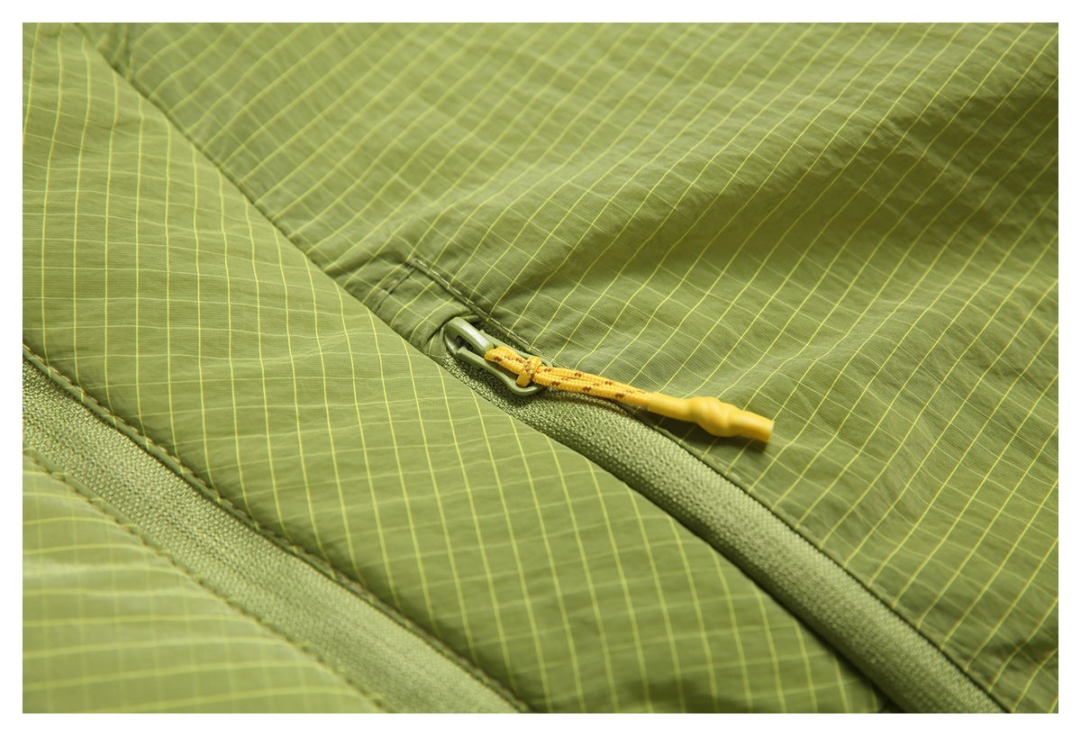 Close-up of an olive-green jacket with a fine yellow grid pattern and yellow zipper pull.