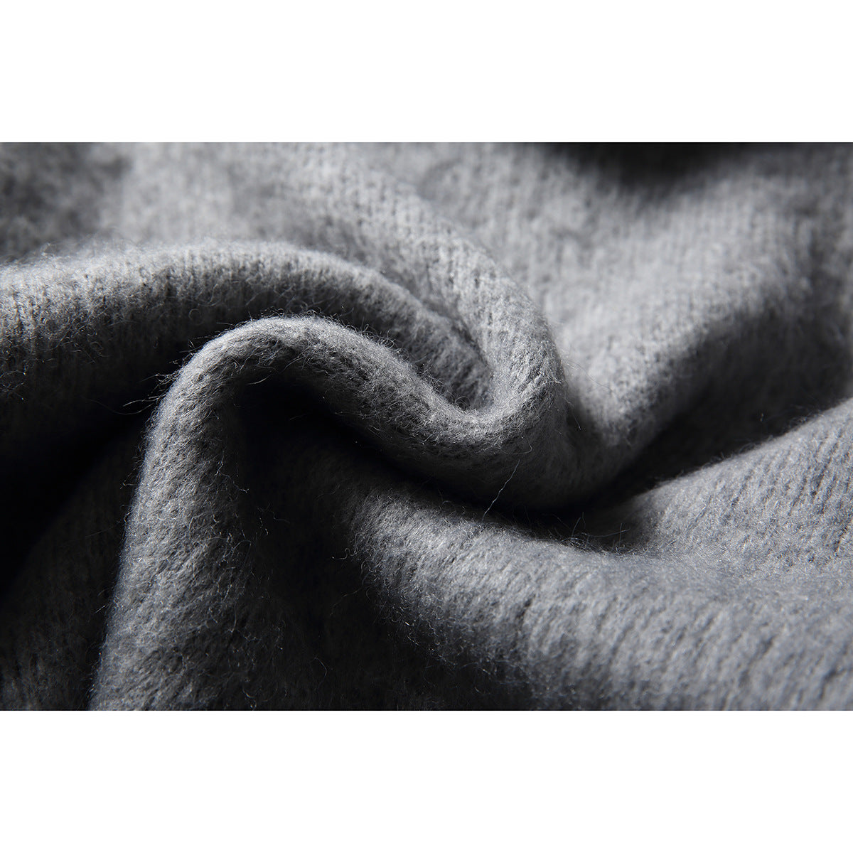 Extreme close-up of the fuzzy gray knit texture and folded edge of a sweater.