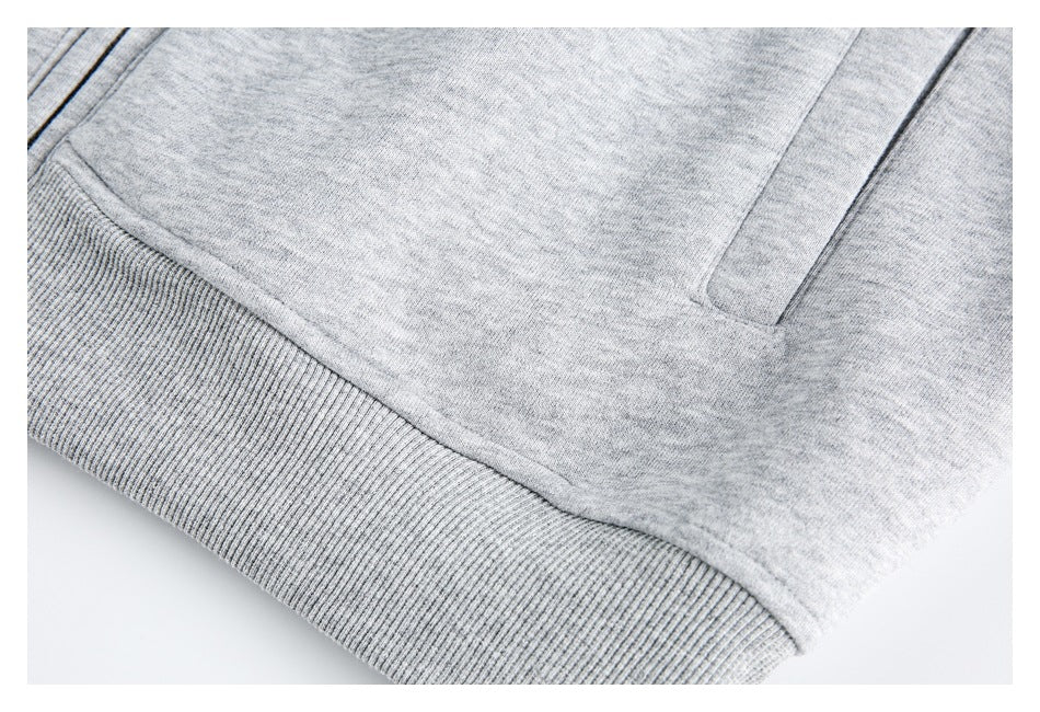 Close-up of a light gray sweatshirt showing its ribbed hem and part of a front pocket.