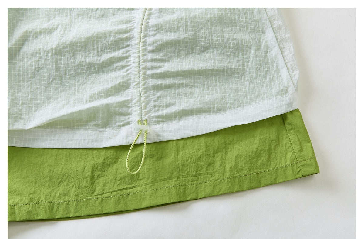 Close-up of the skirt's pale green grid-patterned hem, adjustable drawcord, and solid lime-green underlayer.