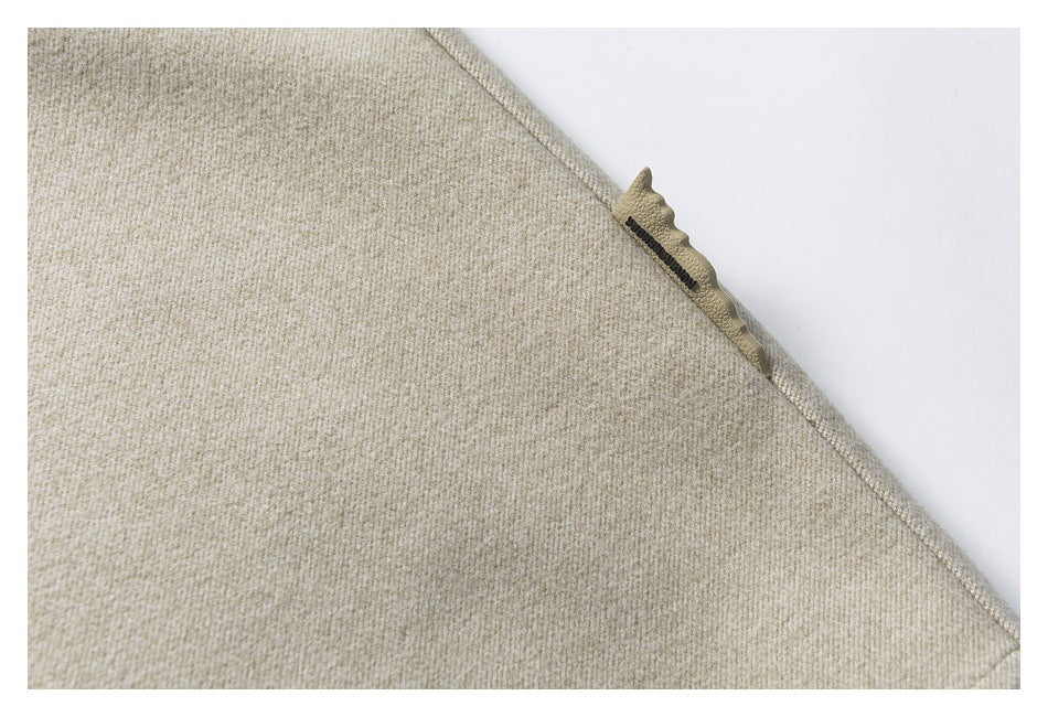 Close-up of beige woven fabric at a seam, with a small tan tab bearing a dark mark.