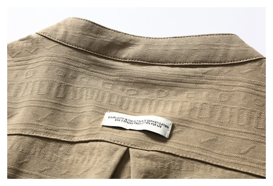 Close-up of the tan shirt's patterned upper back, collar seam, and sewn-in English text label.