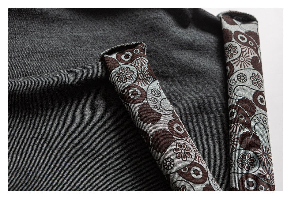 Close-up of charcoal trousers with turned cuffs lined in a brown, gray, and cream geometric floral print.