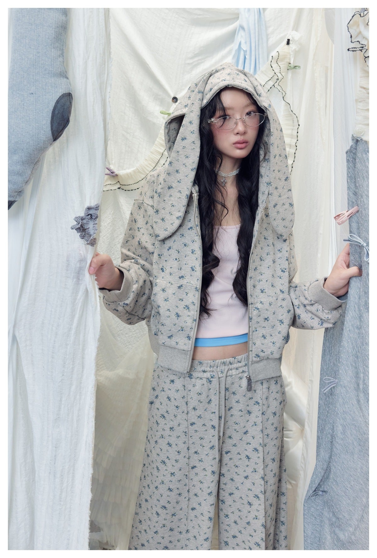 Front view of a model wearing a gray-blue floral-print hooded jacket and matching pants.