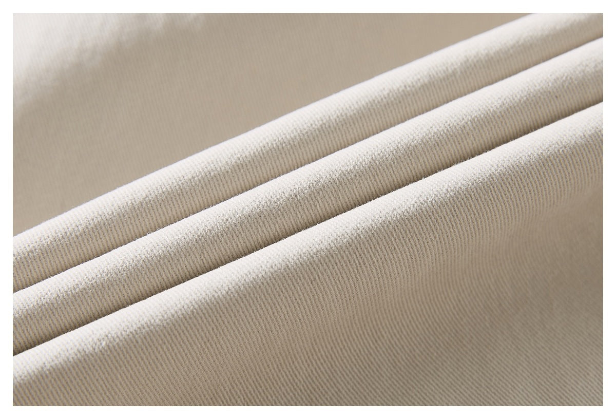 Extreme close-up of the cream trouser fabric, showing its diagonal twill weave and folded ridges.