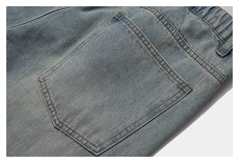 Close-up of a stitched back pocket on light-wash blue denim trousers.