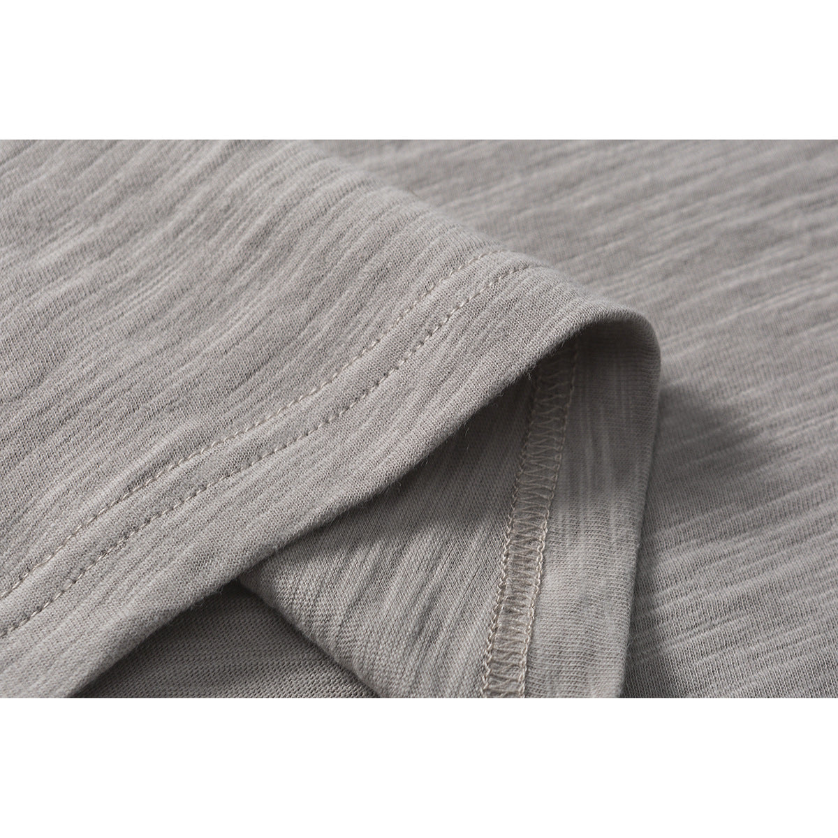 Close-up showing the gray marled T-shirt fabric, folded hem, and overlocked seam.