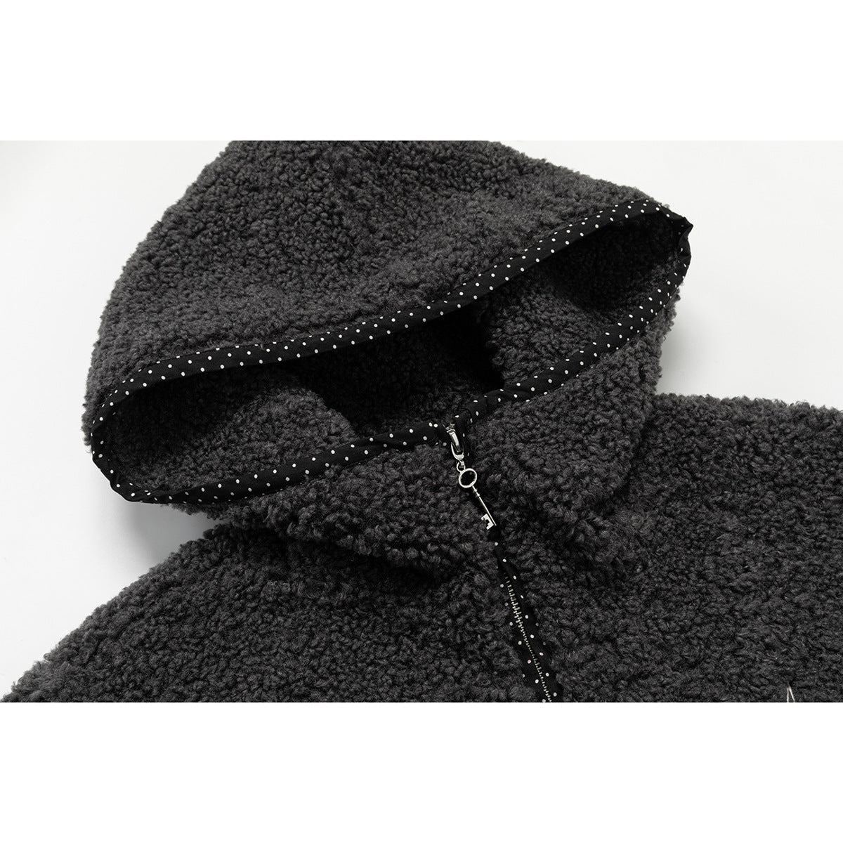 Close-up of a charcoal nubby hood with black-and-white dotted binding and a zipper pull.