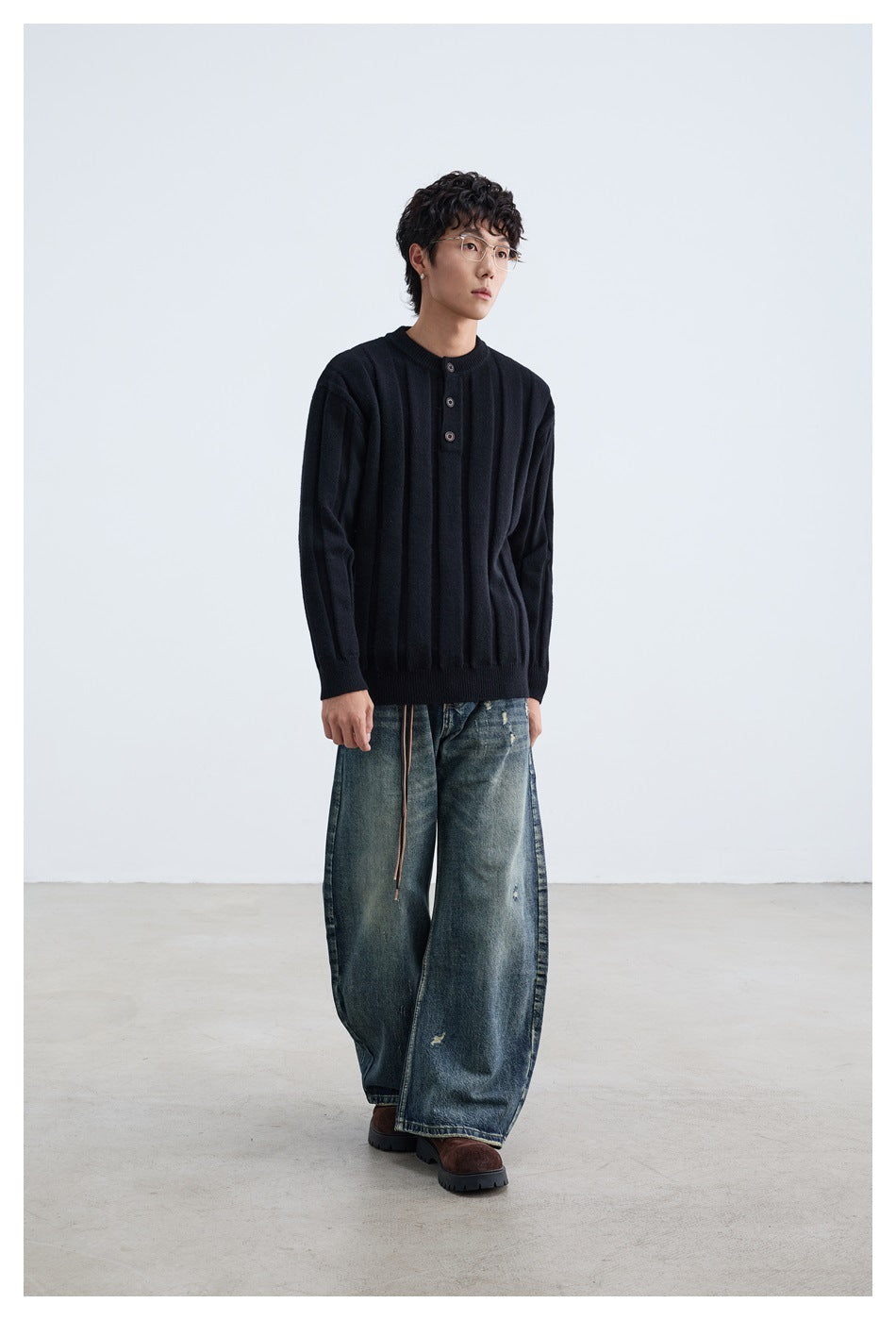 Model wearing a black ribbed sweater with a round neck and three-button placket.