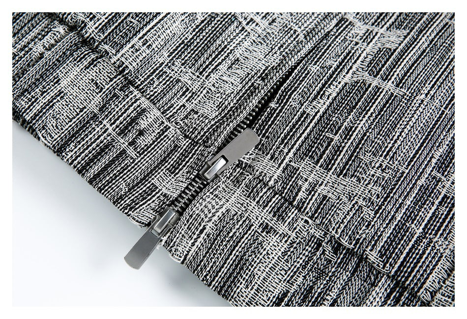 Close-up of a silver zipper on black-and-white textured fabric.