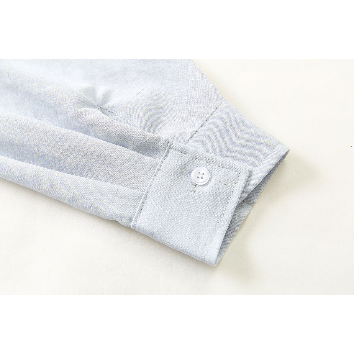Close-up of a pale blue-gray shirt sleeve and buttoned cuff.