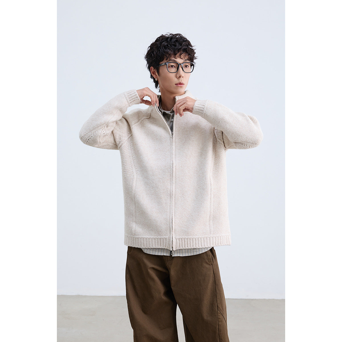 Model wearing an off-white zip-front knit jacket with ribbed details and a stand collar.