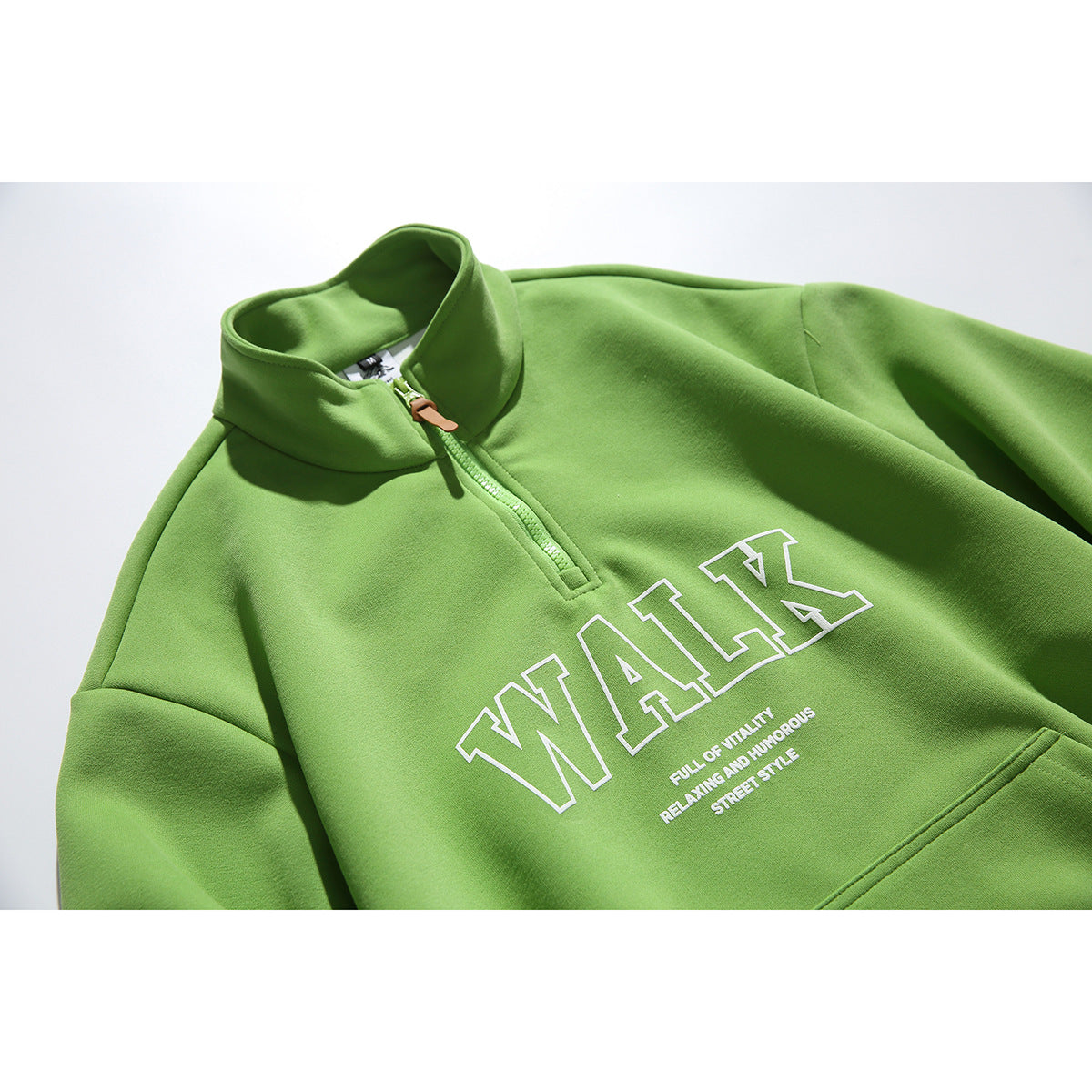 Close-up of a lime-green quarter-zip sweatshirt with a raised collar, kangaroo pocket, and large white outlined chest