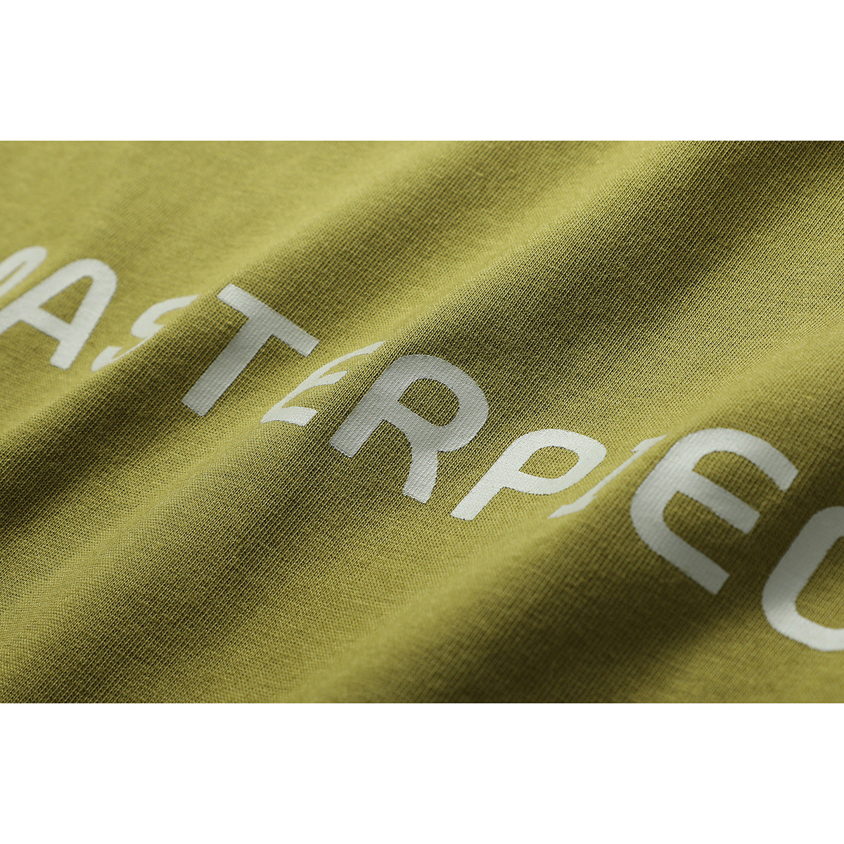 Close-up of olive-green garment fabric with partial white lettering printed across it.
