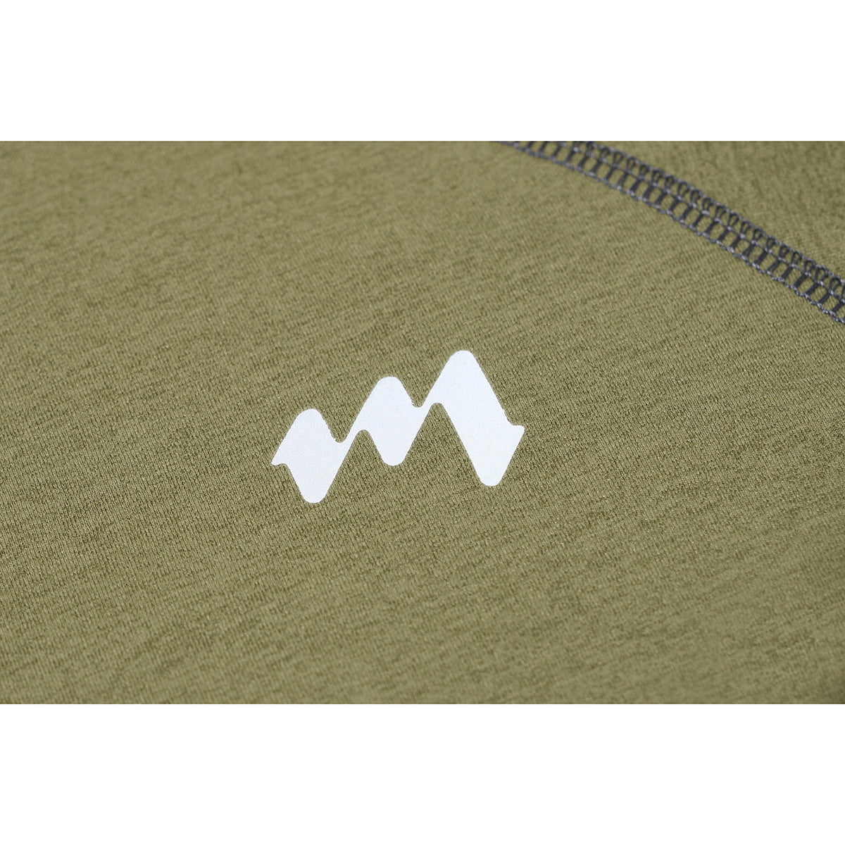 Close-up of a small white zigzag emblem and dark overlock stitching on olive-green shirt fabric.