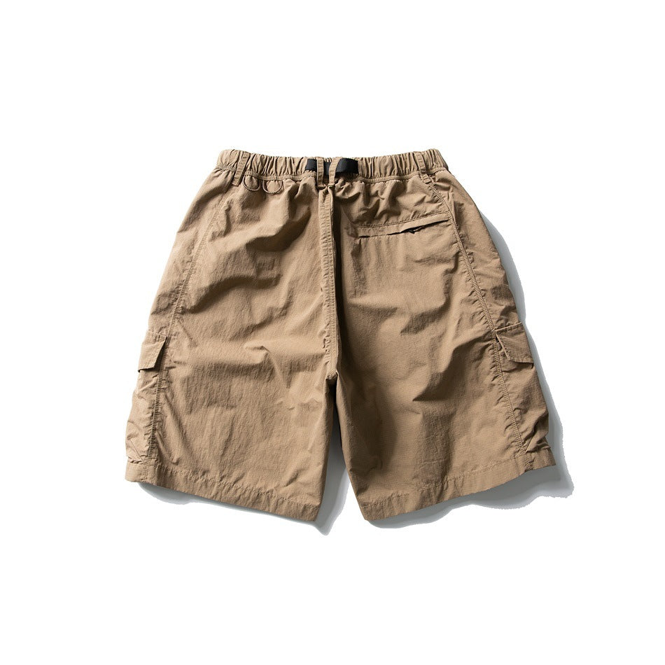 Rear view of tan cargo shorts with an elastic waist, black webbing belt, and side flap pockets.