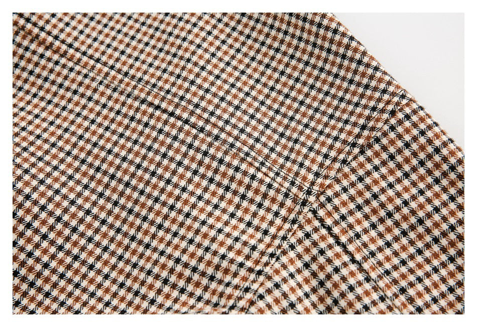 Close-up of a curved stitched seam across brown, black, and cream houndstooth fabric.