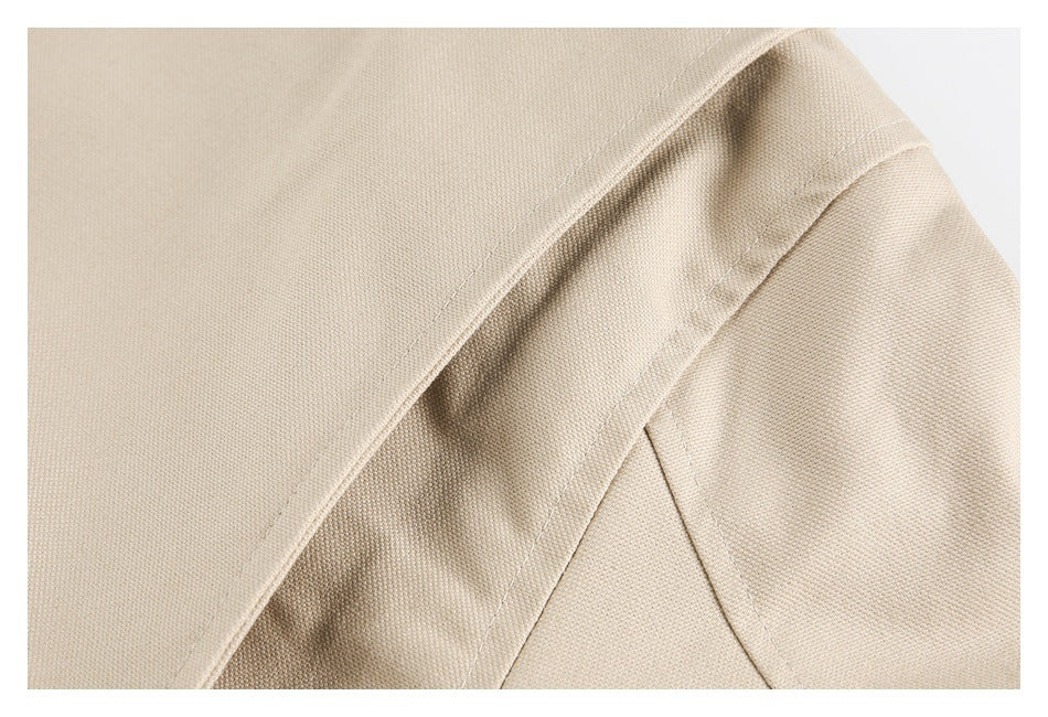 Close-up of beige coat construction, showing stitched seams and a folded fabric edge.