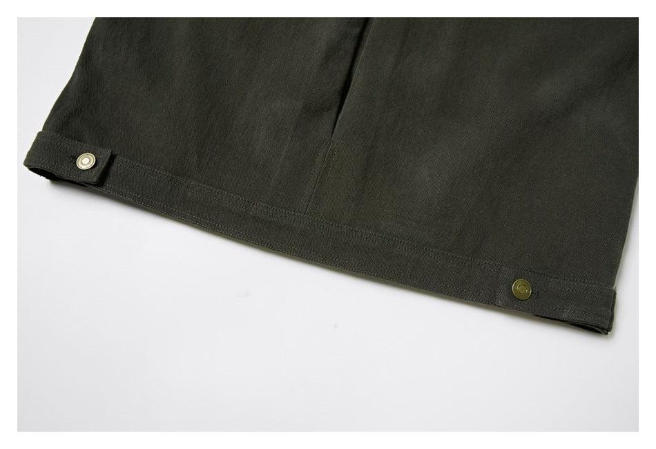 Close-up of a dark olive garment hem with visible stitching and two brass-tone snap buttons.