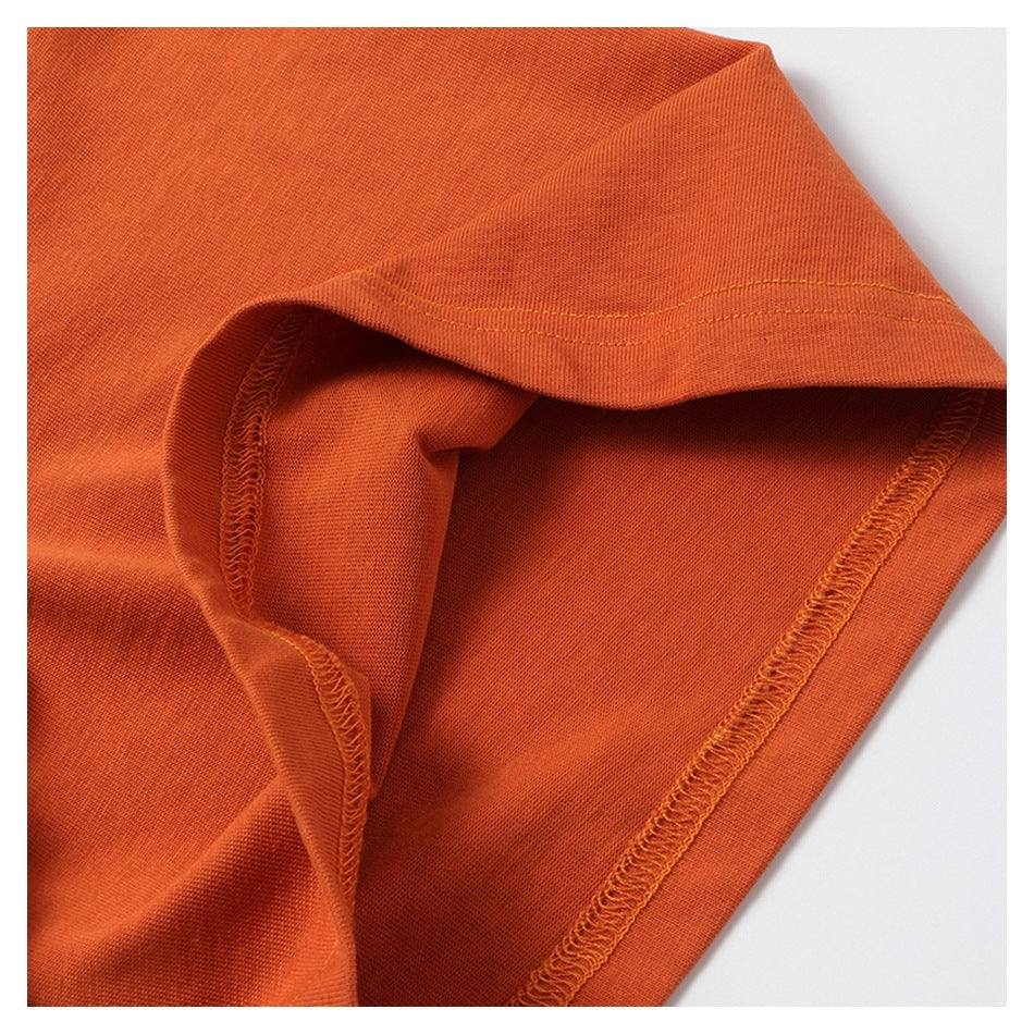 Close-up of orange garment fabric folded to show a hem and inner overlock stitching.