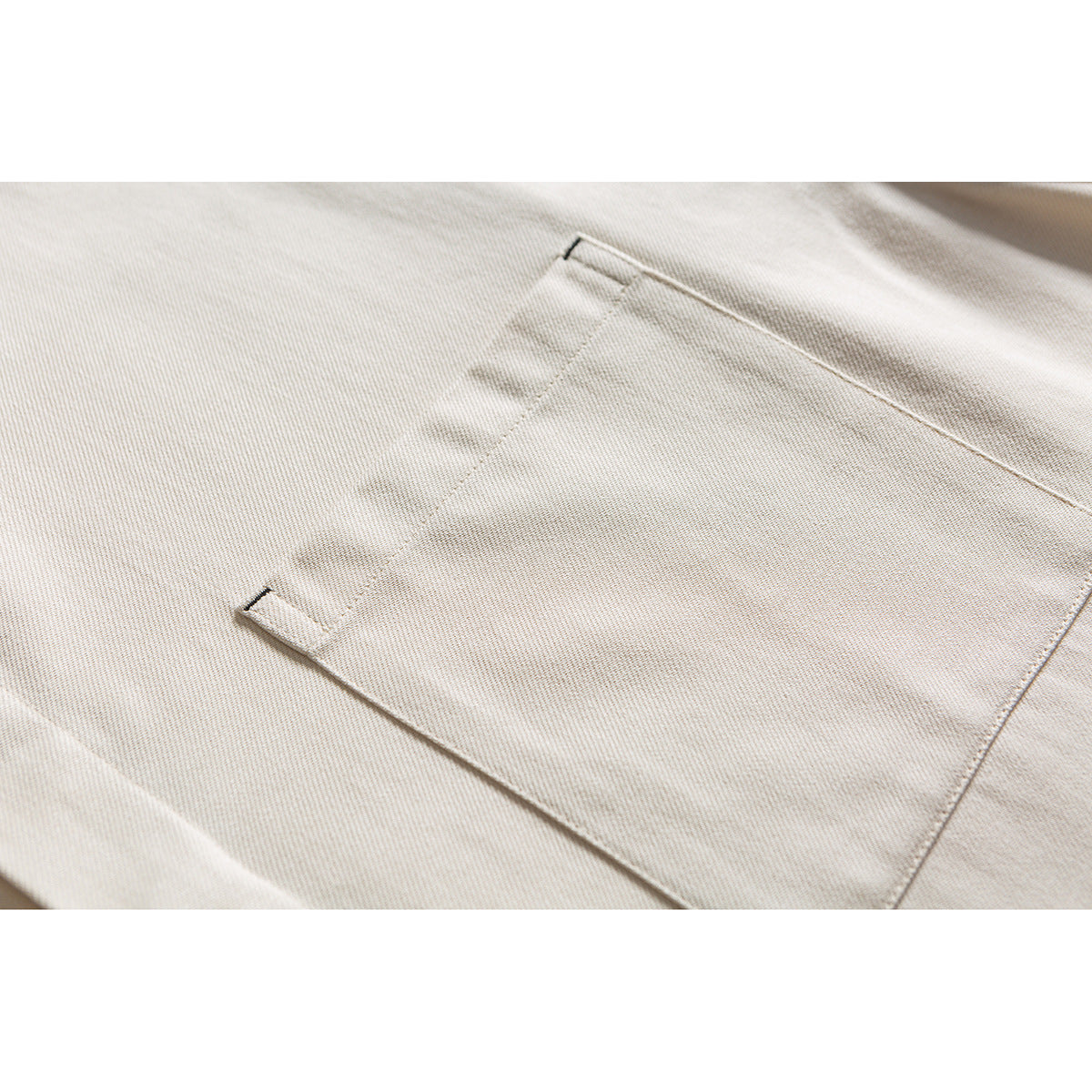 Close-up of a cream shirt's stitched chest pocket.
