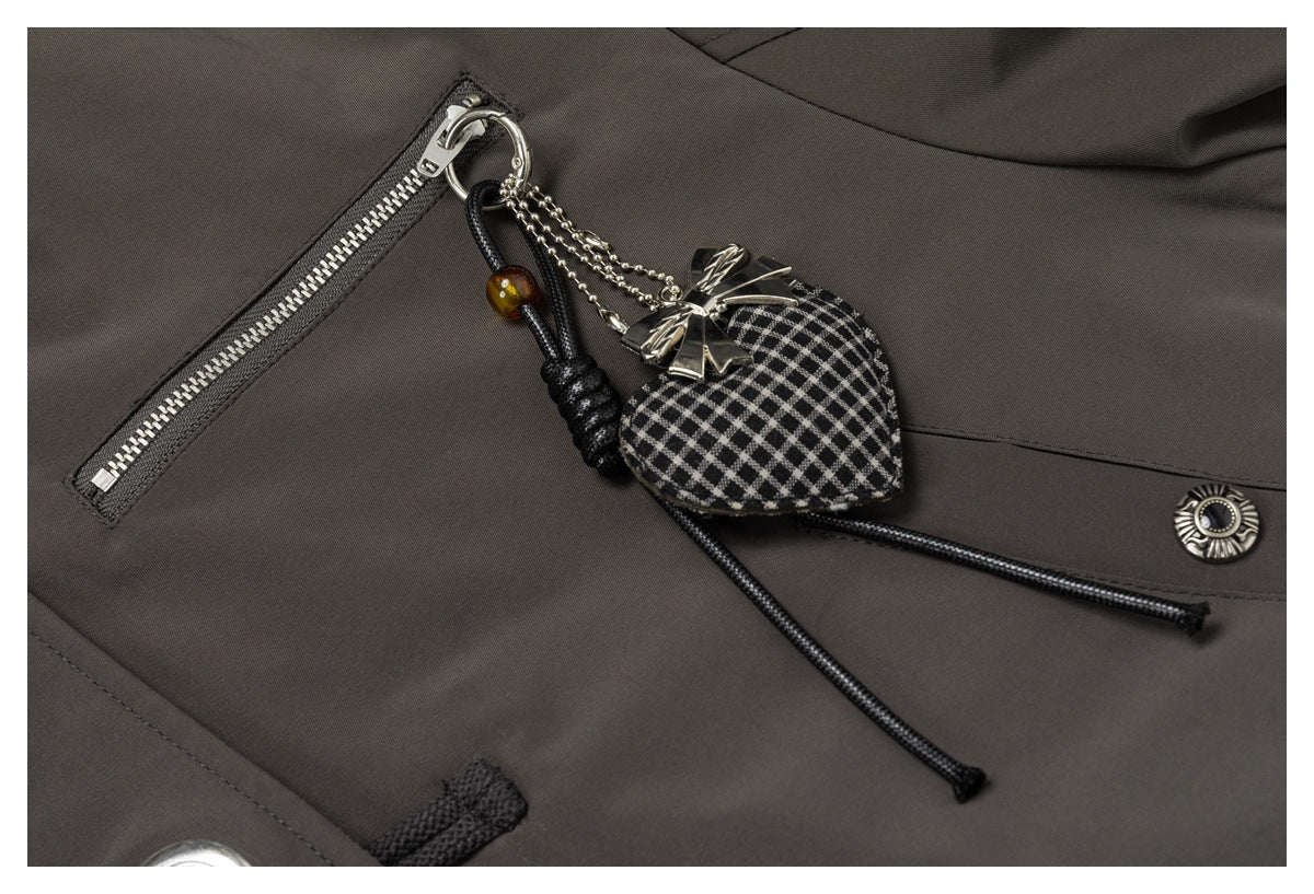 Close-up of a dark charcoal-brown jacket with a silver zipper, decorative heart charm, cord and snap detail.