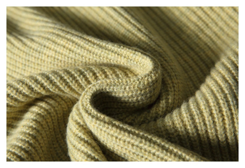 Close-up of pale olive-beige ribbed knit fabric gathered into soft folds.