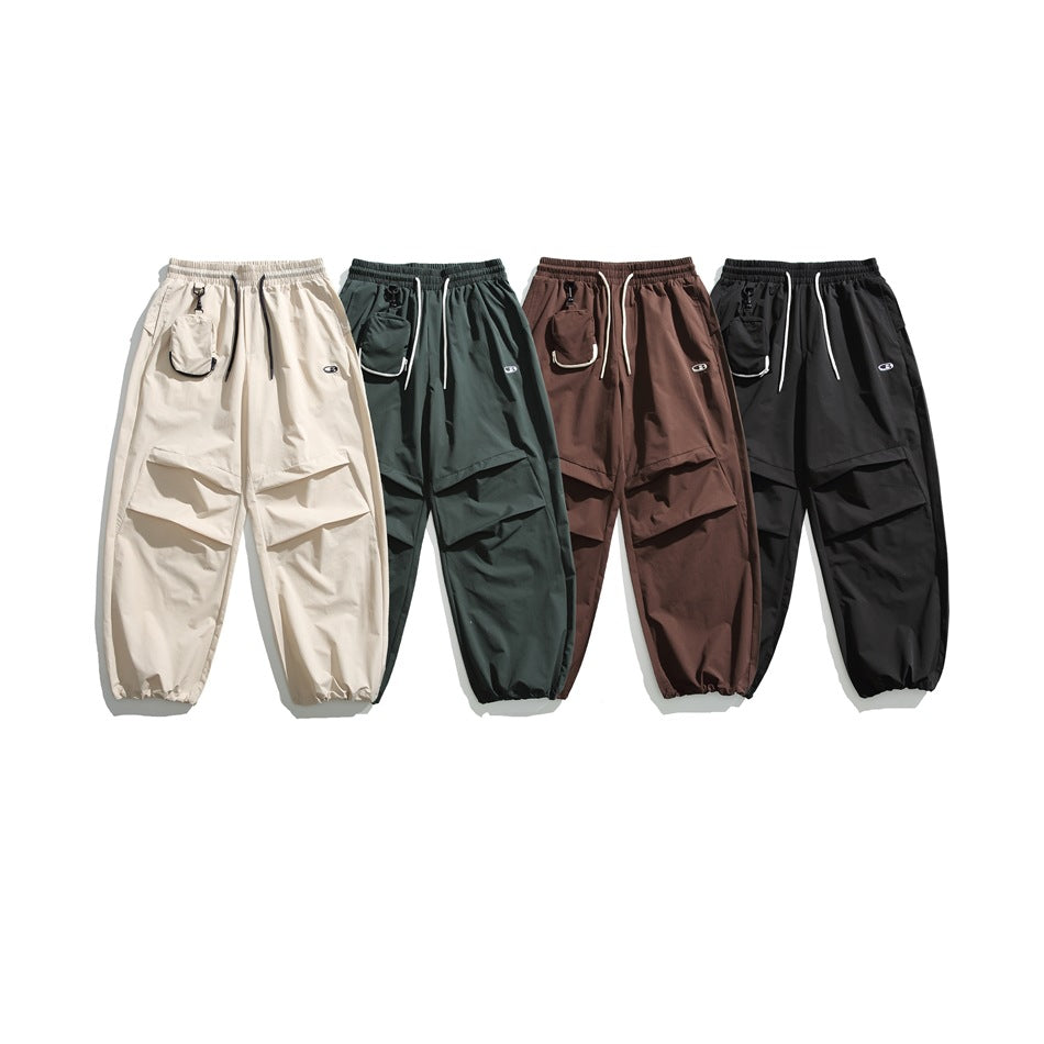 Four loose cargo pants shown side by side in cream, dark green, brown, and black.