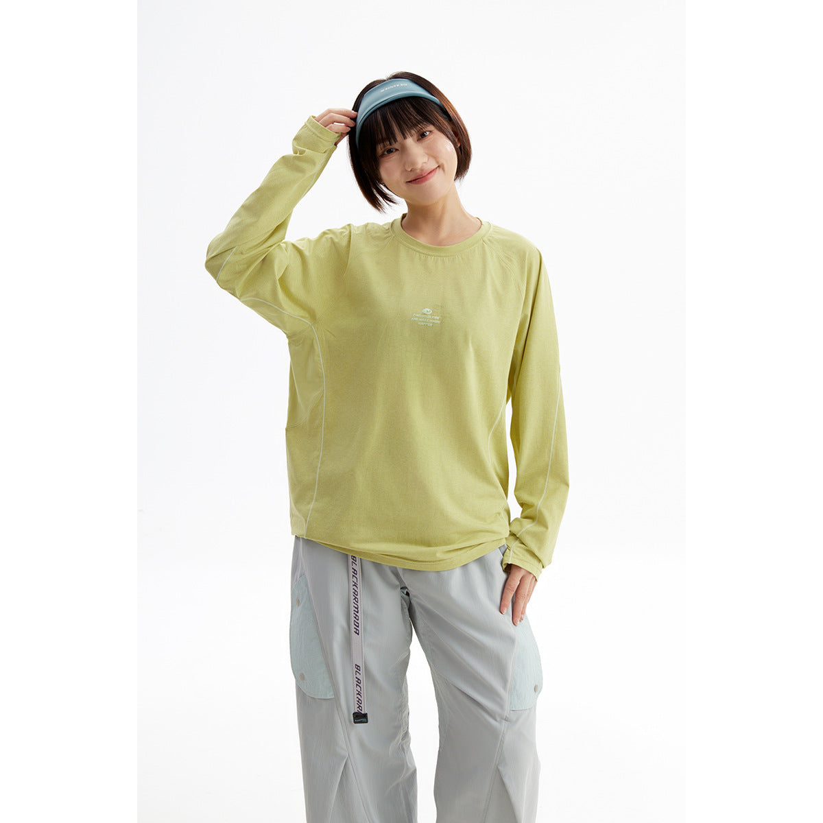 Model wearing a light yellow-green long-sleeve crewneck top with pale piping and extended cuffs.