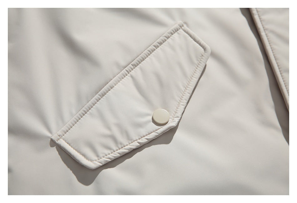 Close-up of a light beige jacket pocket flap secured with a round snap.