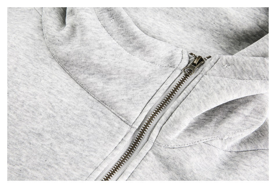 Close-up of the light gray jacket's metal front zipper and stitched hood and collar seams.